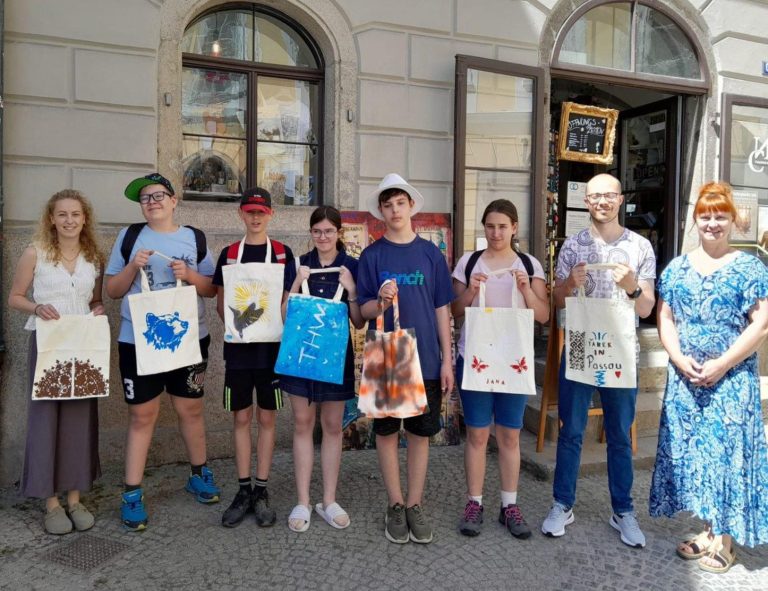 Kunstkurs in der Art Factory ncstreetsart Gruppe von sechs Personen mit bedruckten Taschen vor einem Geschäft.